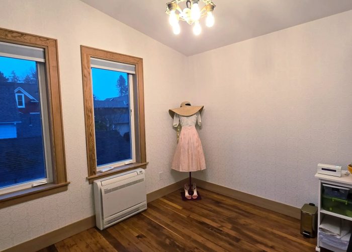 Finished bedroom #4 with white walls, wood floors and two windows.
