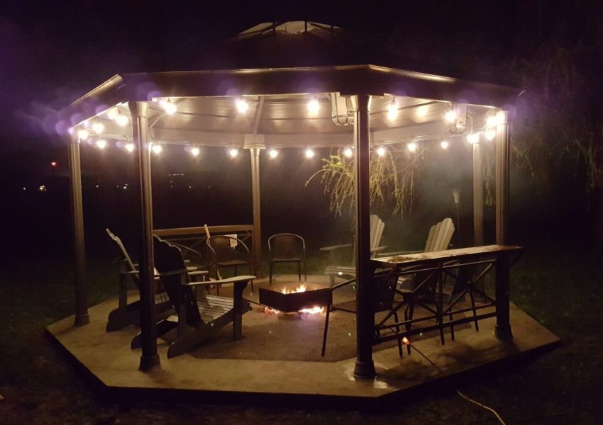 A gazebo at night with a concrete floor and hanging Edison lights.