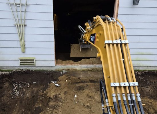 An excavator digging doing groundwork by digging out the basement of a house.