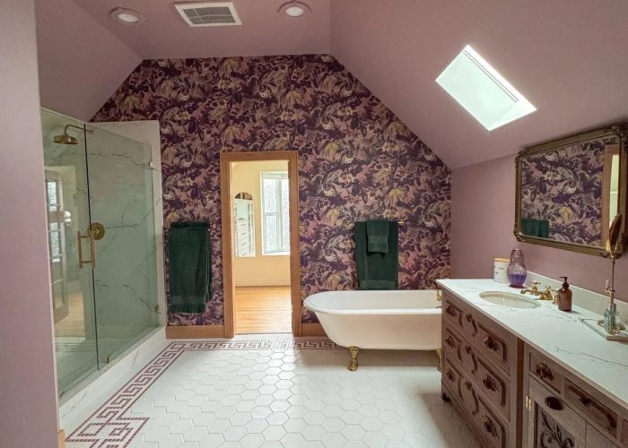 Finished addition primary bathroom with free standing tub, pink paint and pink wall paper.